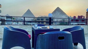 A terrace with wicker furniture and a view of the pyramids. - EQama Pyramids Hotel (Giza)