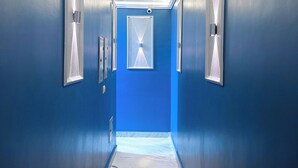 A hallway with blue walls, a marble floor, and recessed lighting. - EQama Pyramids Hotel (Giza)