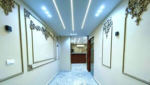 A hallway with marble flooring, ornate wall decorations, and recessed ceiling lights. - EQama Pyramids Hotel (Giza)