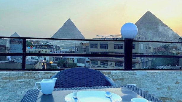 A table set for two with a view of the pyramids in the background. - EQama Pyramids Hotel (Giza)
