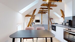 A modern kitchen with a dining area, featuring skylights, wooden beams, and a built-in oven.