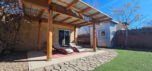 Un patio cubierto con sillones de descanso, un sendero de piedra y una casa al fondo.
