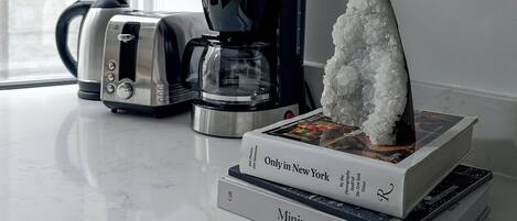 A kitchen counter with a coffee maker, a toaster, and a stack of books.