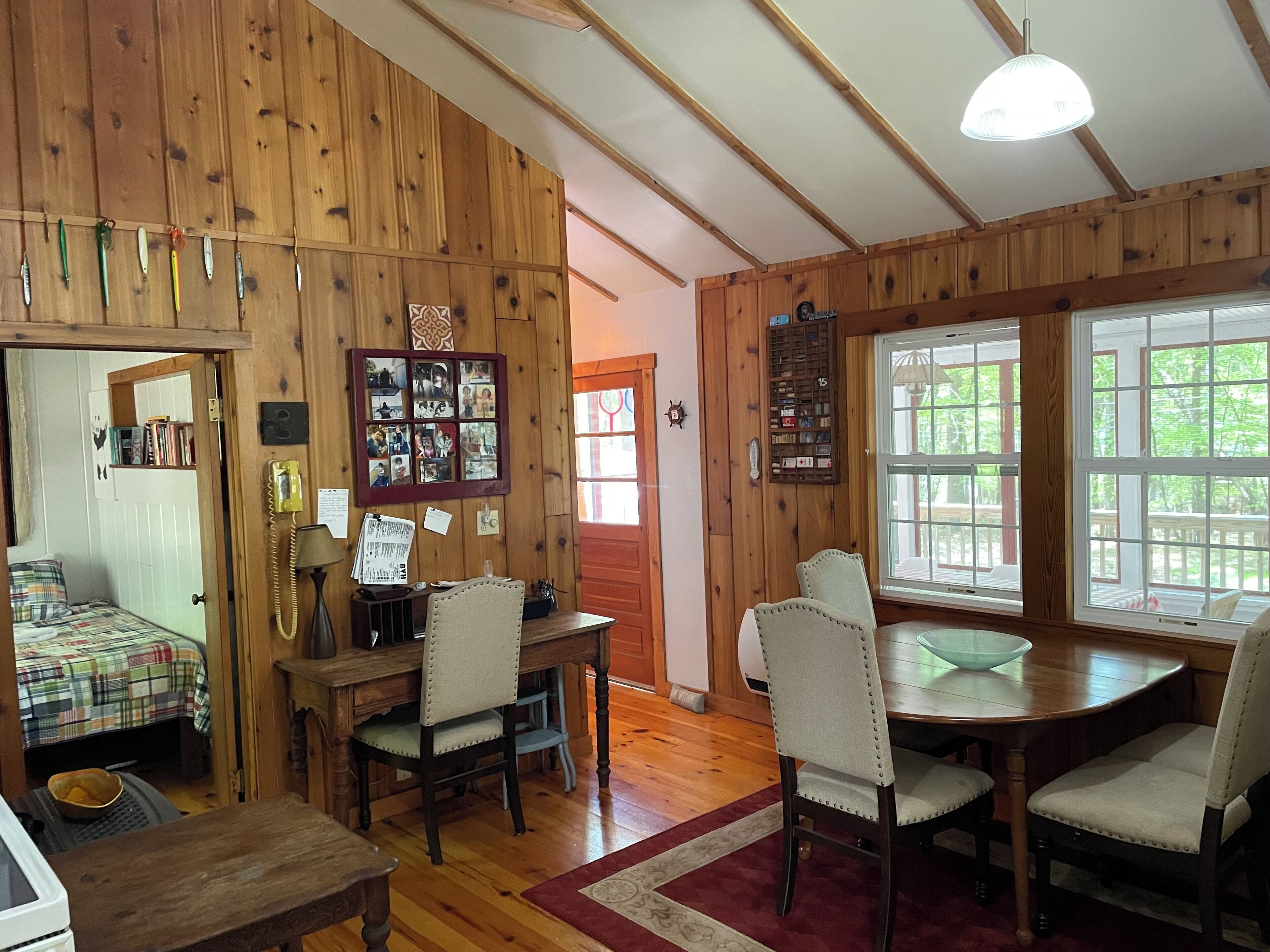 A cozy cabin interior with a dining area, wooden walls, and a large window.