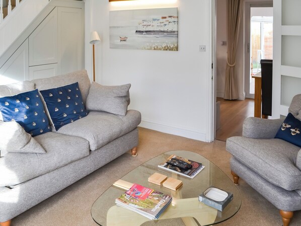 A living room with a grey sofa, a glass coffee table, and a painting on the wall.