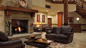 A cozy living room with a stone fireplace, leather sofas, and a staircase.