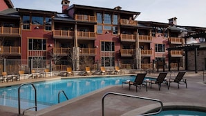 A hotel with a pool area, multiple balconies, and outdoor seating.