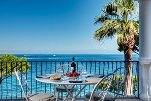 A round table with chairs and a bottle of wine, set against a backdrop of the ocean and a clear sky. - Apt Blu Mare Sorrento Coast (Massa Lubrense)