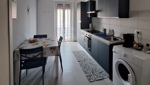 Une cuisine compacte comprenant un coin repas, un lave-linge et une grande fenêtre.