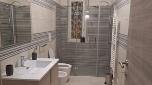 Une salle de bain moderne avec un grand miroir, un lavabo, des toilettes et une douche.