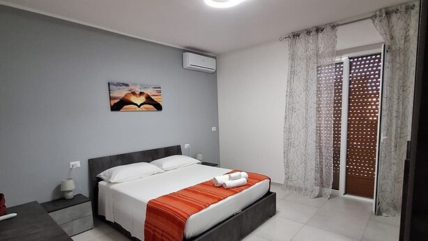 Une chambre à coucher avec un lit, une table de chevet, un bureau et une fenêtre avec des rideaux.