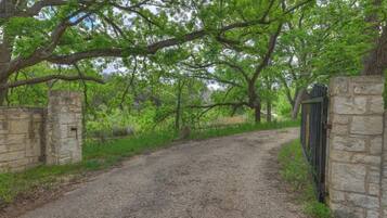 A gravel path flanked by stone walls and lush green trees.