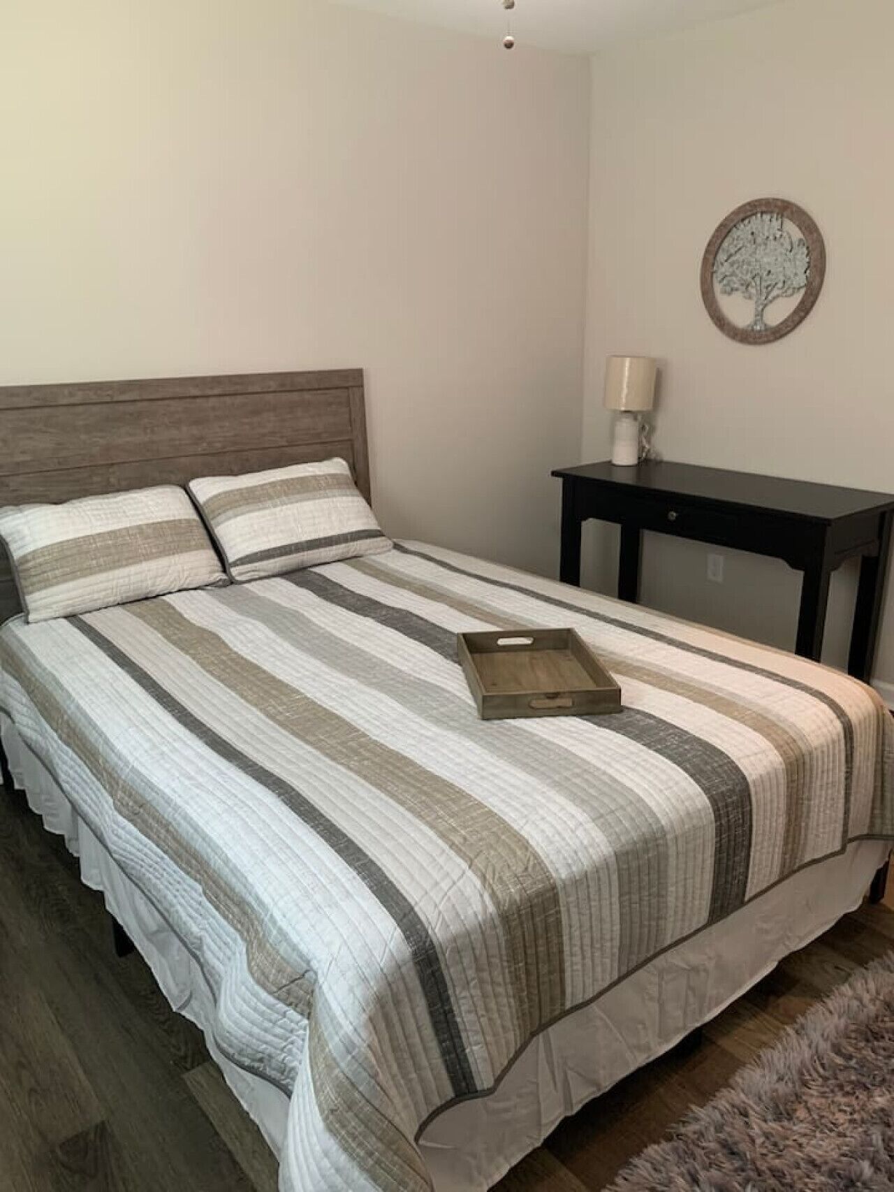 A bedroom with a bed, a nightstand, a lamp, and a wall decoration.