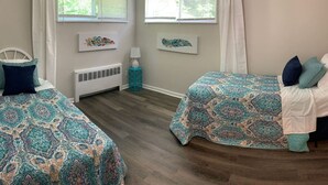 Un dormitorio con dos camas, una ventana, un radiador y obras de arte en las paredes.