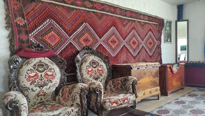 A room with ornate wooden furniture, including a sofa and a chair, a wooden chest of drawers, and a patterned rug. - Dede Sebo Camping (Dogubayazit)