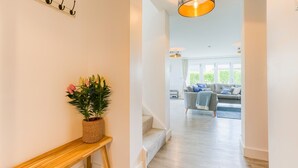 Ein Flur mit einer hölzernen Bank, einem Blumentopf und einer Treppe, die in einen Wohnbereich mit einer Couch und einer Lampe führt.