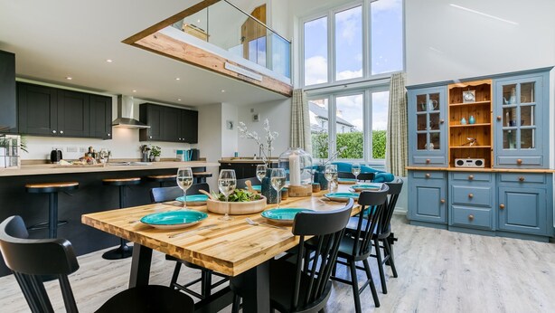 Eine moderne Küche mit einem Holzespeisetisch, schwarzen Stühlen und einem blauen Schrank mit Glastüren.