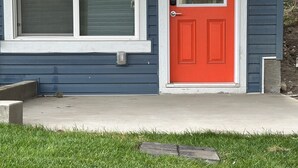 A house with a red door, a window with a white frame, and a small porch area.