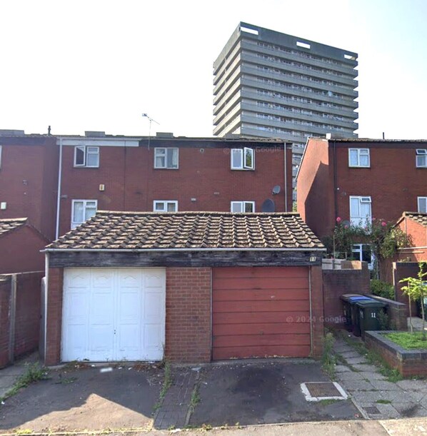 A residential building with a red garage door, a tiled roof, and a brick facade. - Homestays - Modern House Near Coventry City Centre (Coventry)