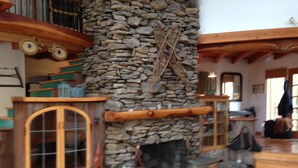 Ein Kamin aus Stein mit hölzernem Sims, eine Steinwand und eine Holztreppe.