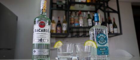 A bar setting with two bottles of Bacardi and Olmeca Tequila, and three glasses on a counter.