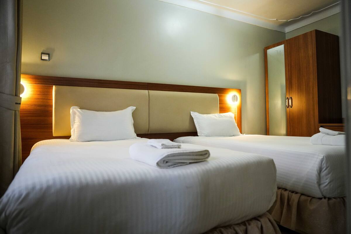 A hotel room with two beds, a wooden headboard, and a large mirror.