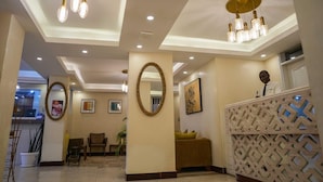 A hotel lobby with a reception desk, seating area, and decorative lighting. - ENN Business hotel (Entebbe)