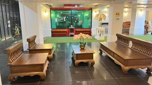 Un vestíbulo con bancos de madera, mostrador de recepción y una zona alfombrada en color verde.