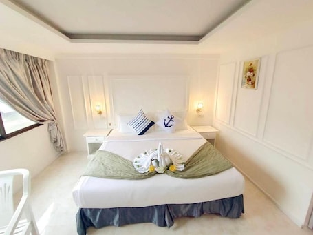 A hotel room with a neatly made bed, a bedside table with a lamp, and a window with curtains.