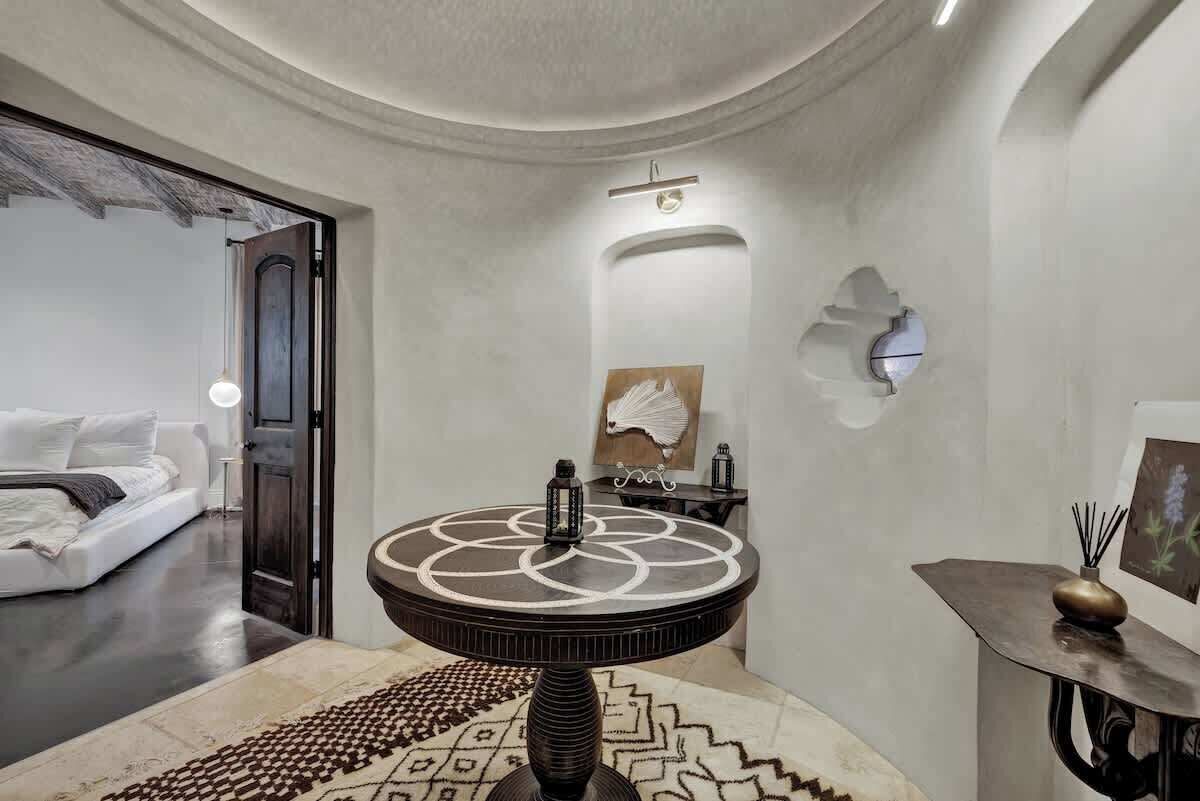 Ein modernes Interieur mit einem runden Tisch, einem weißen Sofa und einem gemusterten Teppich.