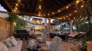 Eine Terrasse im Freien mit Steinboden, Gartenmöbeln und Lichterketten.