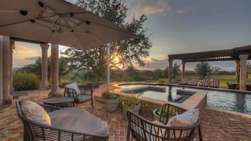 Una piscina al aire libre, sombrillas, sillones reclinables de piscina