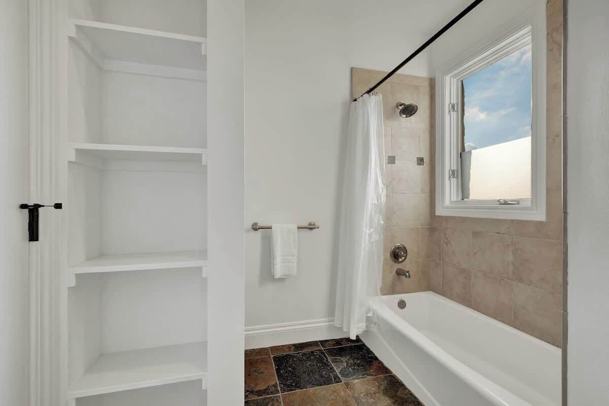 Un baño con bañera, cortina de ducha y ventana.