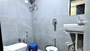 A small, tiled bathroom with a toilet, bidet, and a sink. - Hotel Bhavya Raj (Gandhinagar)