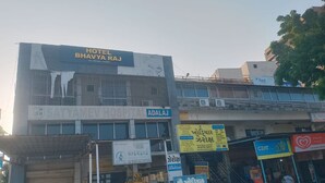 A building with a sign for Hotel Bhavya Raj and Satya Mev Hospital. - Hotel Bhavya Raj (Gandhinagar)