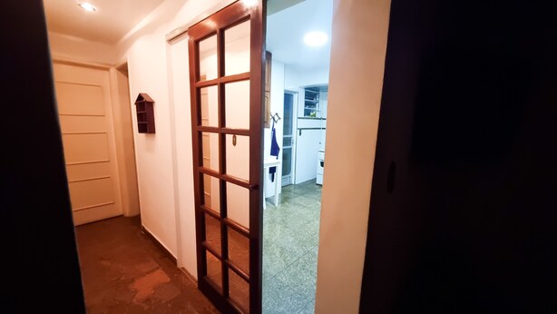 A hallway with a wooden door leading to a kitchen area. - Beachfront Apartment, Prime Location (Centro Cabo Frio)