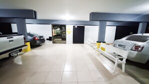 A parking garage with white tiled floors, benches, and a white pickup truck. - Beachfront Apartment, Prime Location (Centro Cabo Frio)