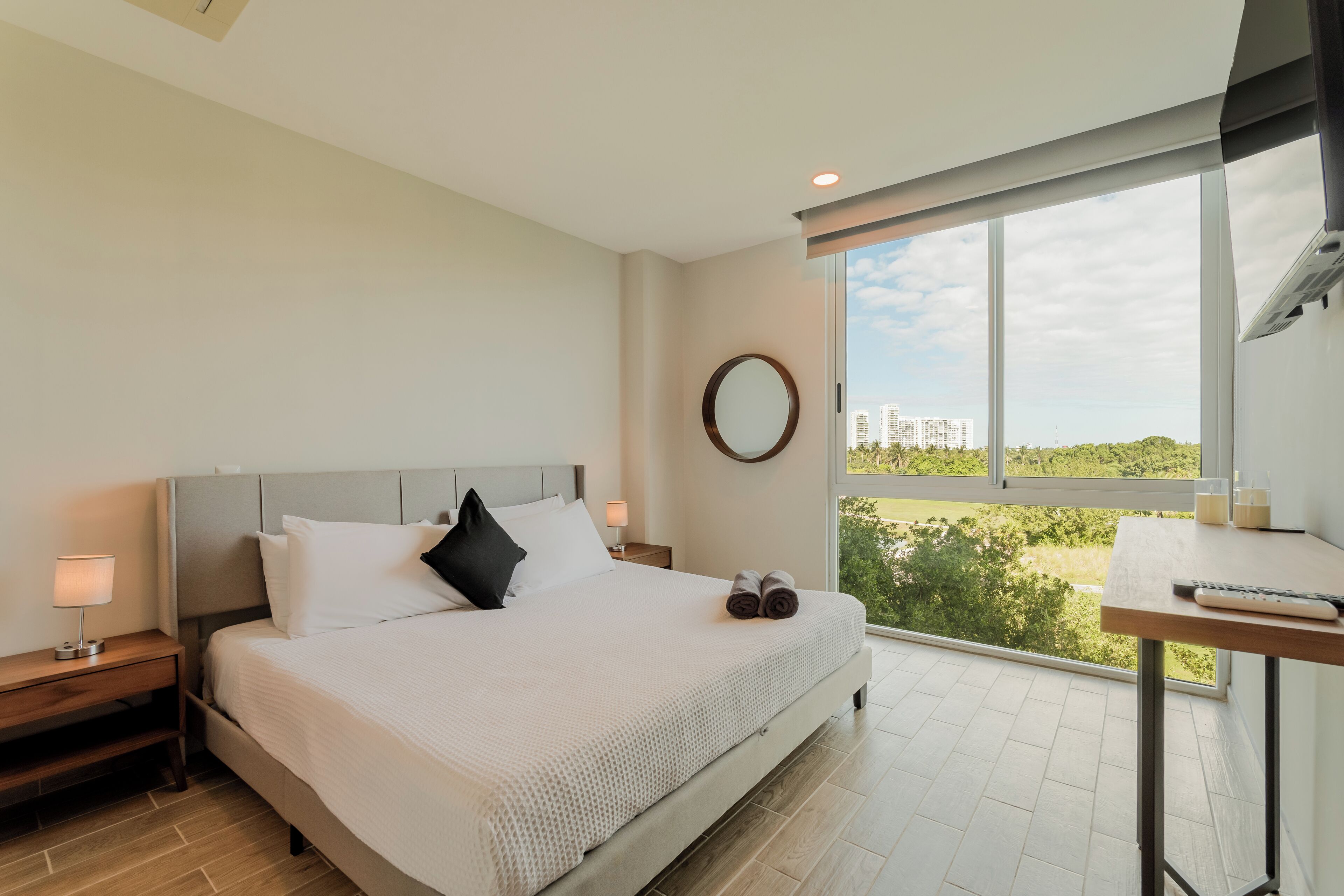 Una camera d'albergo moderna con un letto grande, una scrivania e vista sulla città.