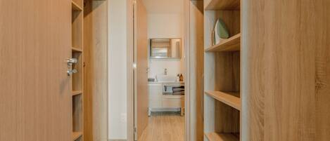 A wooden hallway leading to a bathroom with a sink and mirror.