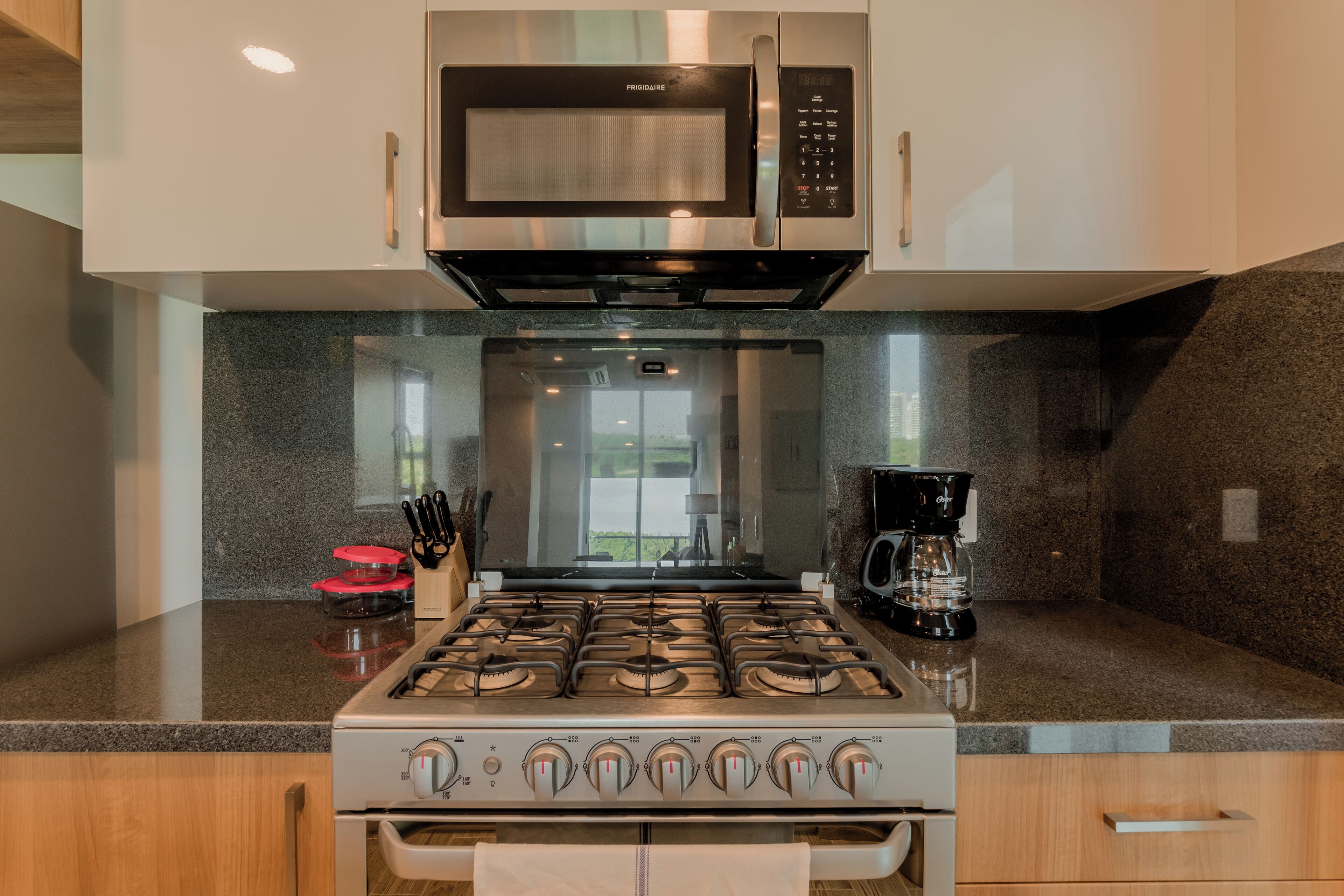 A modern kitchen with a stainless steel microwave, a gas stove, and a coffee maker.