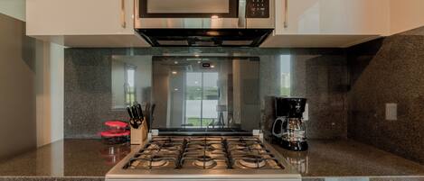 A modern kitchen with a stainless steel microwave, a gas stove, and a coffee maker.