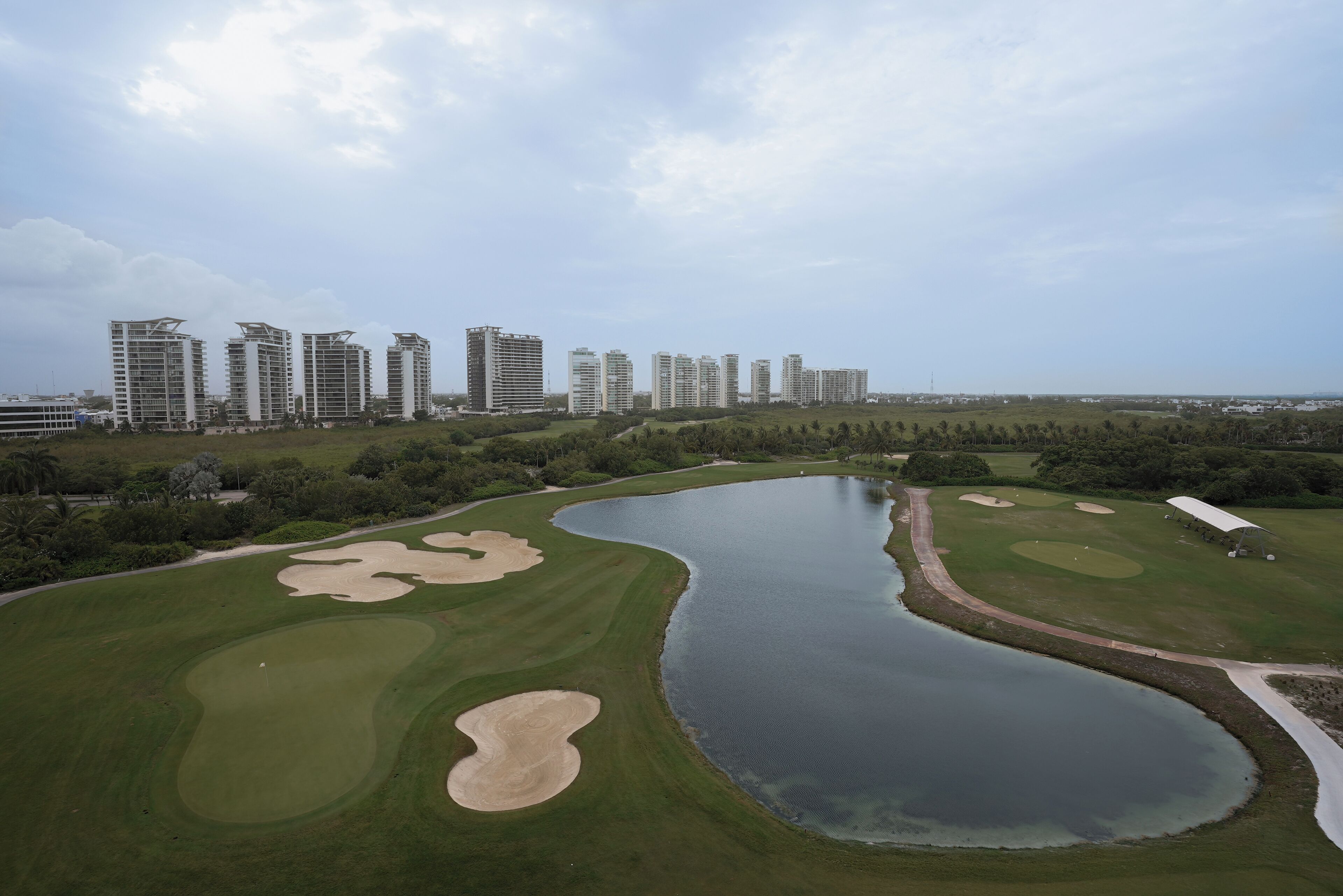 A golf course with bunkers, a water hazard, and a clubhouse.