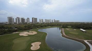 A golf course with bunkers, a water hazard, and a clubhouse.
