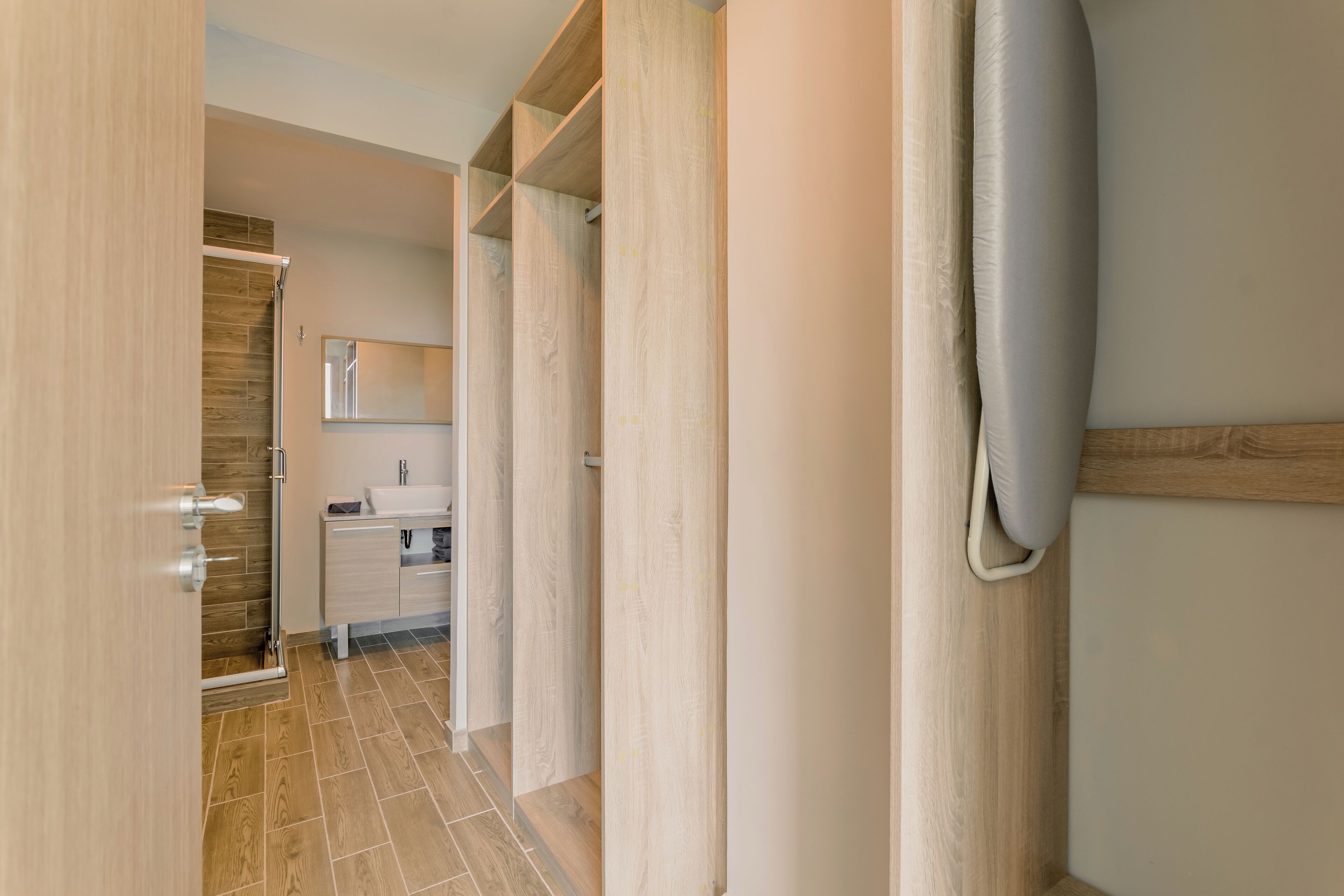A modern bathroom with a wooden vanity, a mirror, and a shower area.