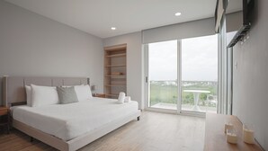 Een moderne slaapkamer met een groot bed, inbouwkasten, een balkon met een tafel en uitzicht op de omgeving.