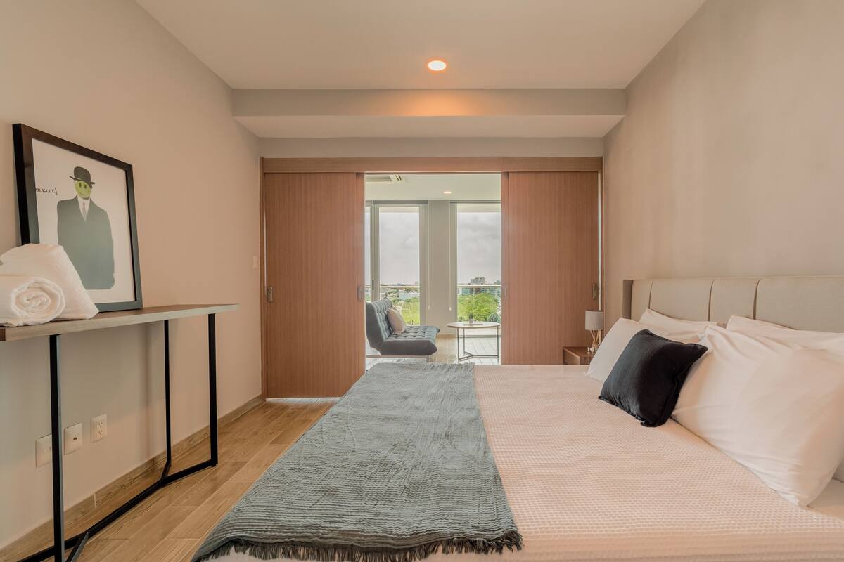 Ein Hotelzimmer mit Bett, Schreibtisch, Handtuch und Blick ins Freie.