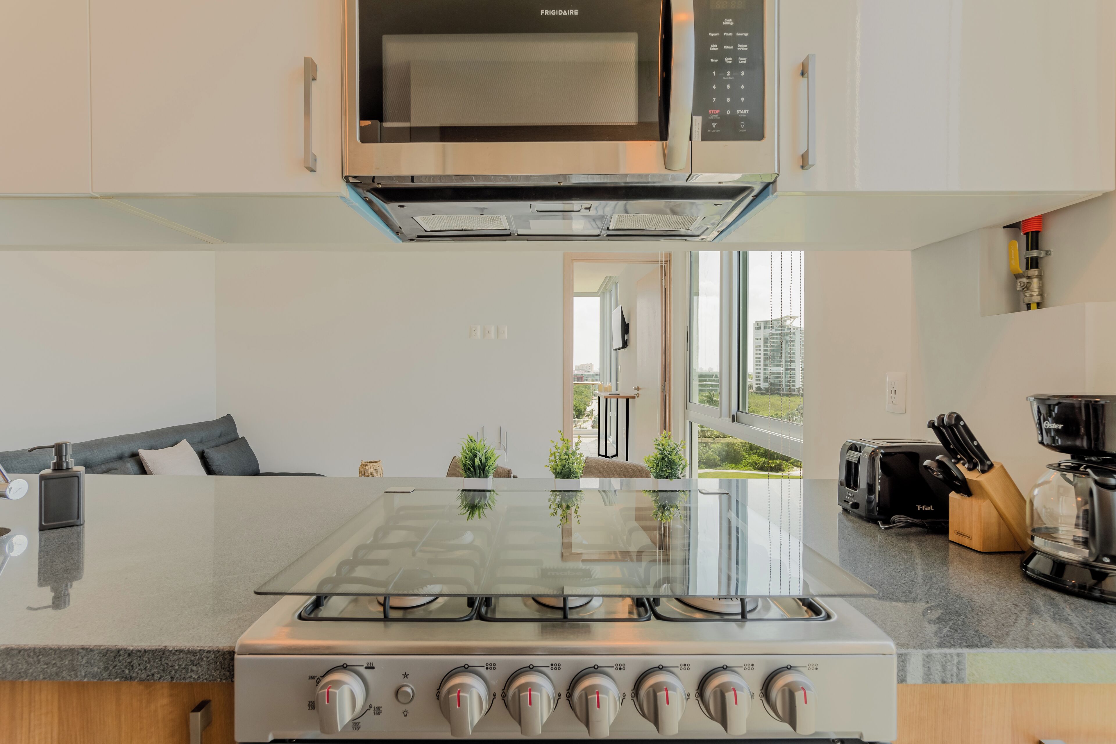 A modern kitchen with a central island, stainless steel appliances, and a view to the outdoors.