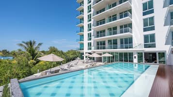 Relax by the pool surrounded by lush greenery and palm trees.