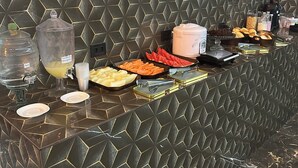 Un buffet proposant une variété de plats et un distributeur d’eau.