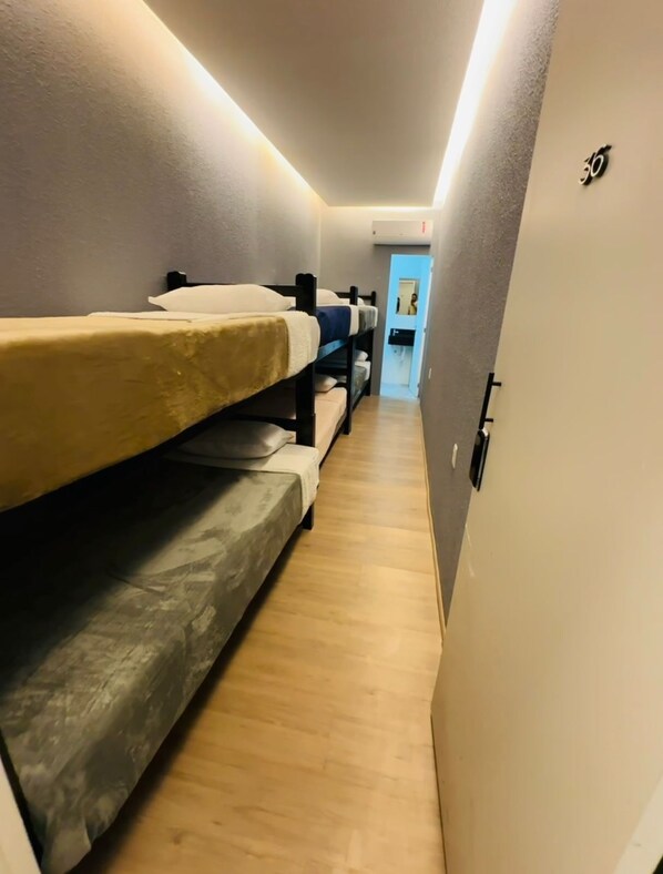 A narrow hallway with bunk beds on one side and a door on the other. - On Hotel campos do Jordao centro Capivari e passeio quadriciclo (Campos do Jordão)